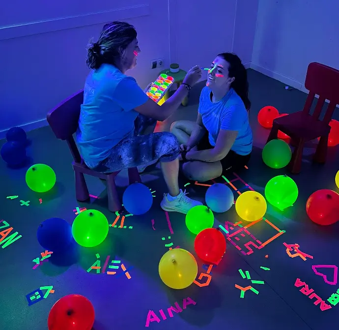 mujer pintandole la cara con pintura fluorescente a chica mujer pintandole la cara con pintura fluorescente a chica